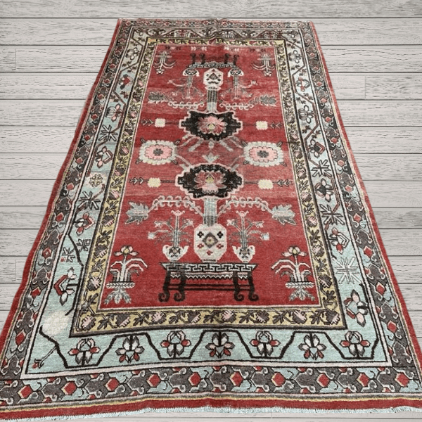 A character-rich antique Khotan rug with a deep red field and rare figurative table motifs. Layered, symbolic, and highly decorative, this piece offers both narrative and refined presence, 4'7" x 6'7"